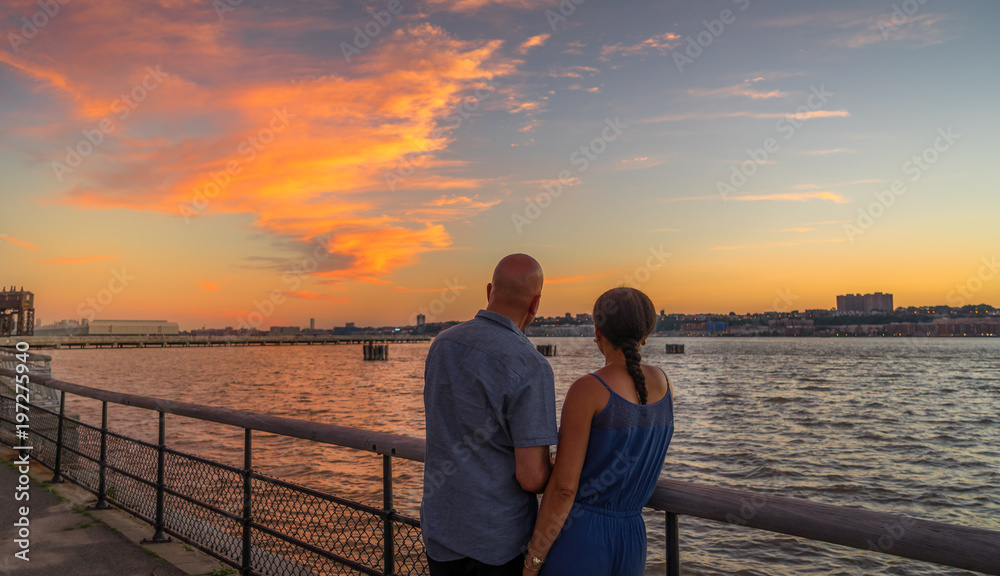 Fototapeta premium Couple watching beautiful sunset at riverside park, Manhattan NY