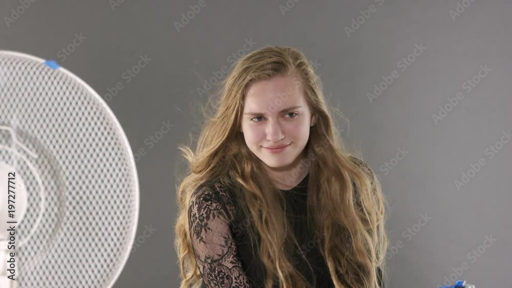 Studio portrait photography. Young model poses for photographer. Teen girl in black dress poses on grey background. Backstage shot during photoshoot. Studio portrait photography. Young model poses for photographer. Teen girl in black dress poses on grey background. Backstage shot during photoshoot.