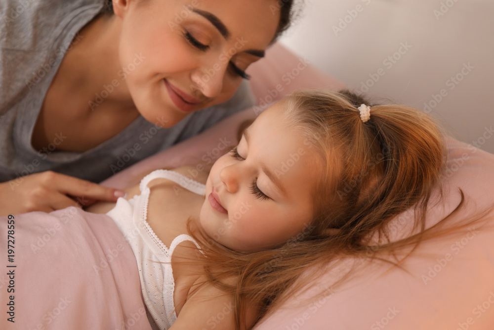 Mother looking at her cute little daughter sleeping in bed at home Mother looking at her cute little daughter sleeping in bed at home