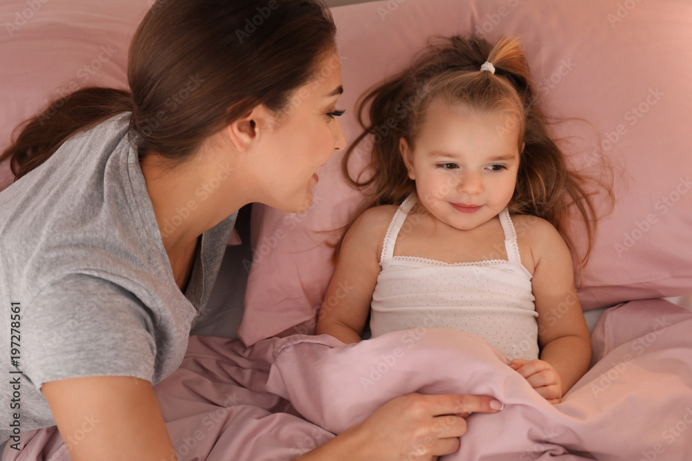 Mother putting her little daughter to bed at home Mother putting her little daughter to bed at home