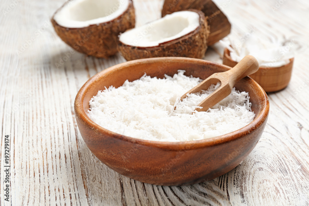 Fresh coconut flakes in bowl on wooden background Fresh coconut flakes in bowl on wooden background