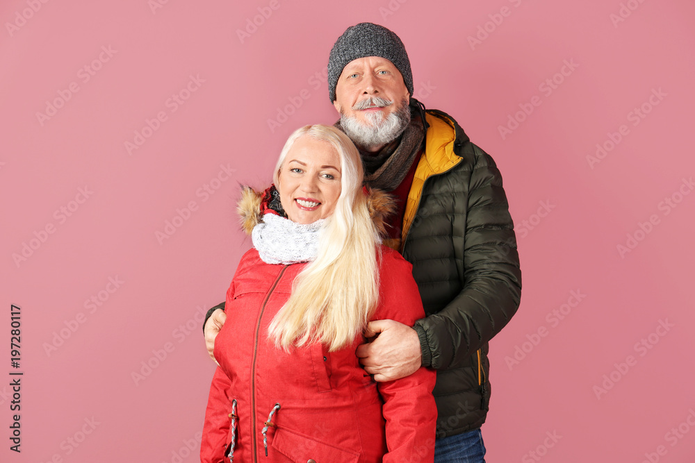 Mature couple in warm clothing on color background. Ready for winter vacation