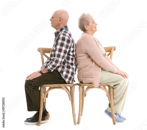 Elderly couple sitting on chairs against white background