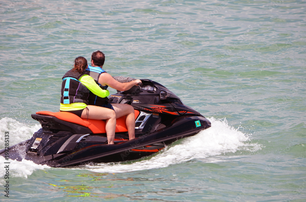 Young couple riding tandem on a jet ski on the florida intra-coastal waterway off Miami Beach.