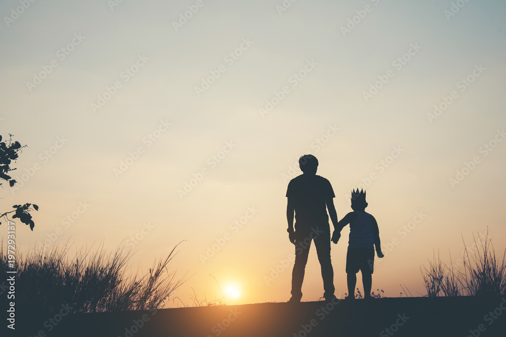 Silhouette of father and son standing together.