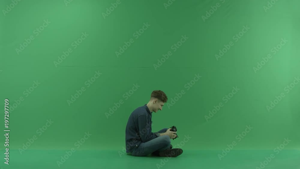 Cross-legged on the right hand side photographer looking photos and rejoice the results on the green screen Cross-legged on the right hand side photographer looking photos and rejoice the results on the green screen