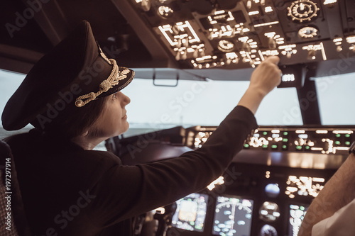 Female pilot the captain of the plane prepares for take-off in the plane cockpit. Girl pilot in uniform flying craft plane in the sky