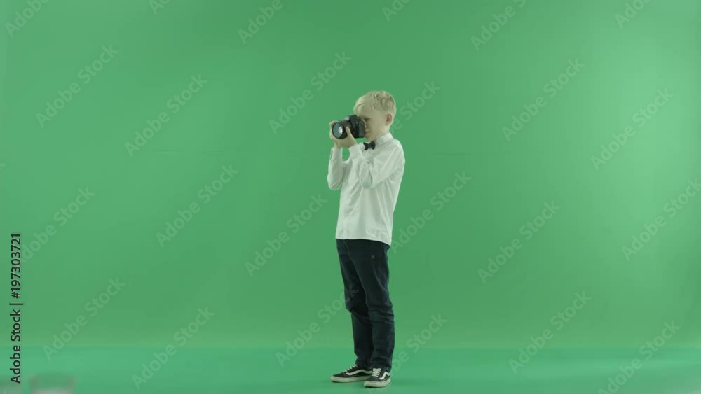 The child is taking photos on the front left hand side on the green screen and makes some corrections
