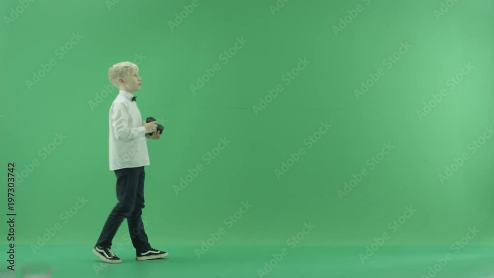 The child is walking and taking photos on the left side of the green screen The child is walking and taking photos on the left side of the green screen