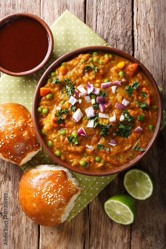 Pav Bhaji Indian spicy fast food with bread Paav close-up on the table. Vertical top view