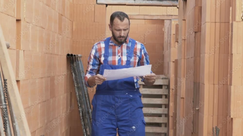 Young male worker with blueprints checking home at construction site
Young male worker with blueprints checking home at construction site