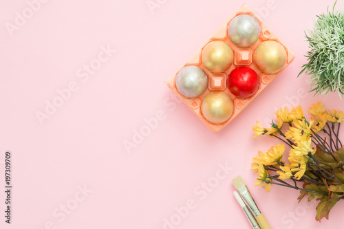 Flat lay top view colorful easter egg painted in pastel colors composition and spring flowers with paint brush on pink pastel color background. Easter day background top view with copy space.