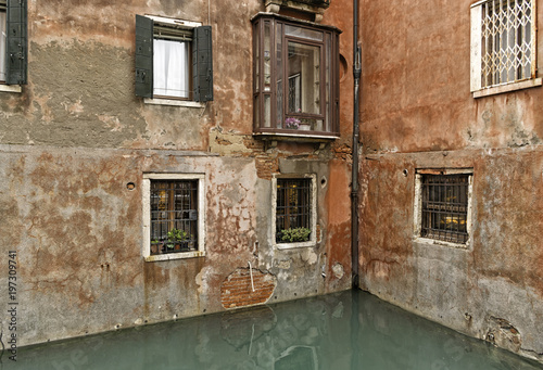 A hidden corner of old traditional Venetian buildings with red bricks and concrete on a canal in Venice, Italy. Typical Italian architecture