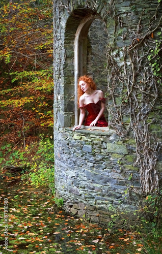 beautiful red hair lady looking out of a old castle window
