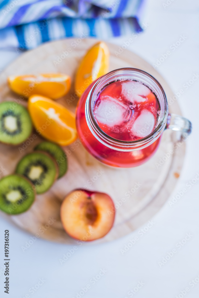 Red fruit lemonade with ice in a jar and fresh tropical fruits on a wooden tray - top view Red fruit lemonade with ice in a jar and fresh tropical fruits on a wooden tray - top view