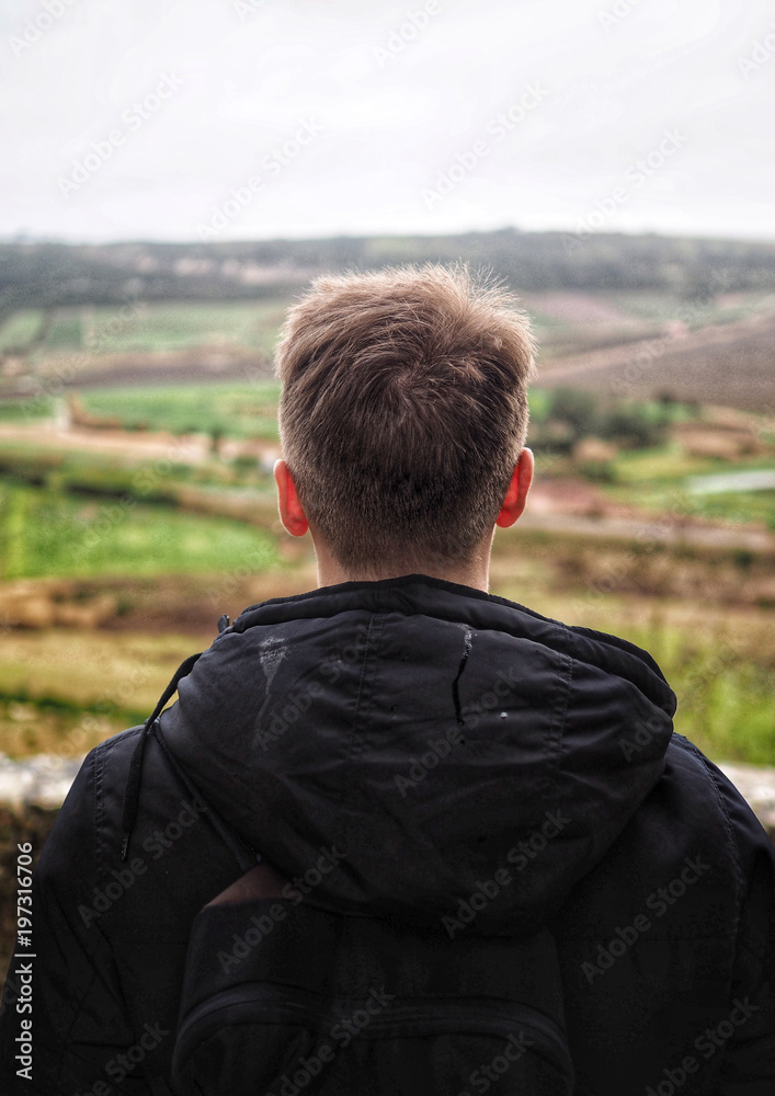 A blond man from behind, enjoying view of green fields, Portugal.