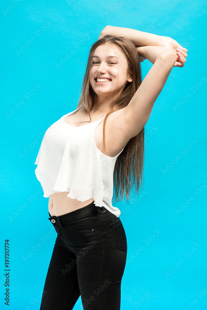 Relaxed Young girl with a broad smile on her face and hands behind her head on a blue background Relaxed Young girl with a broad smile on her face and hands behind her head on a blue background
