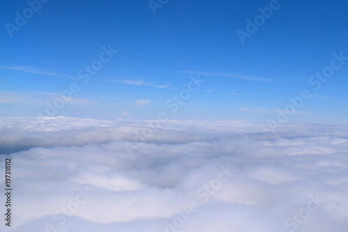 Cloud formations from above and below in a blue sky, photographed from the ground and from an airplane