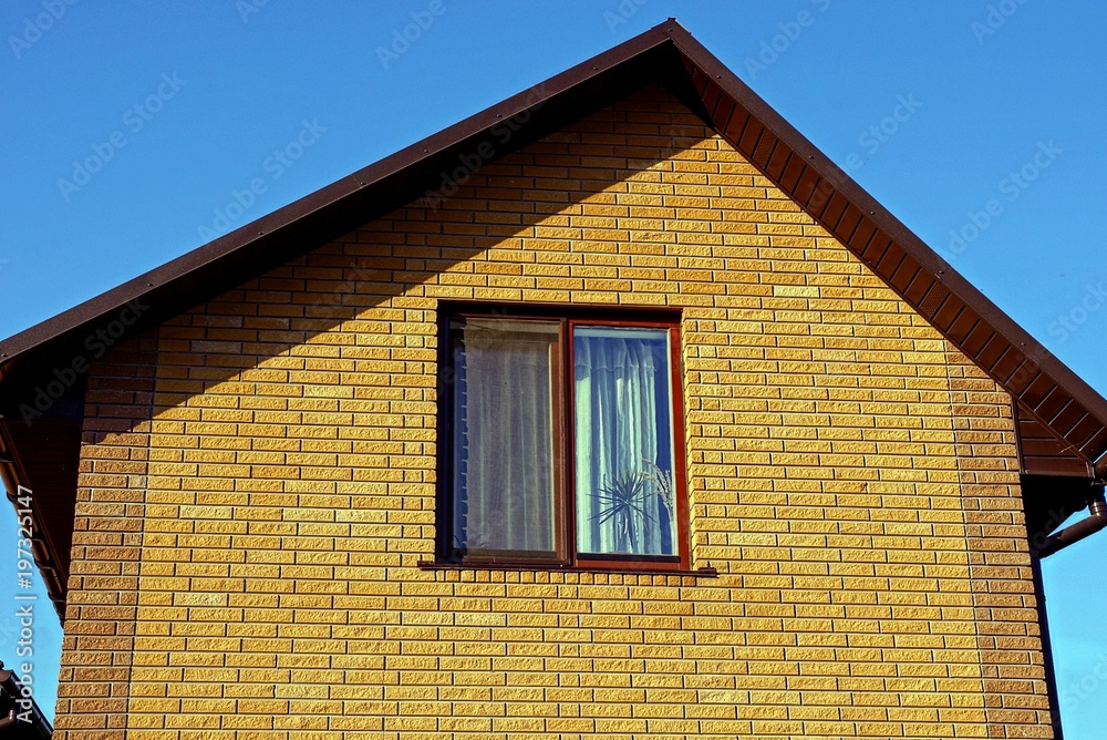 facade of a brown house with a window against the blue sky