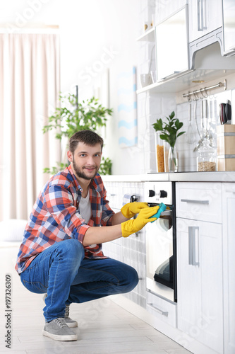 Young man cleaning oven in ...