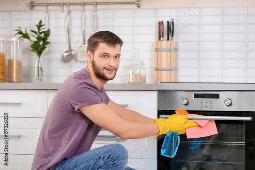 Young man cleaning oven in ...