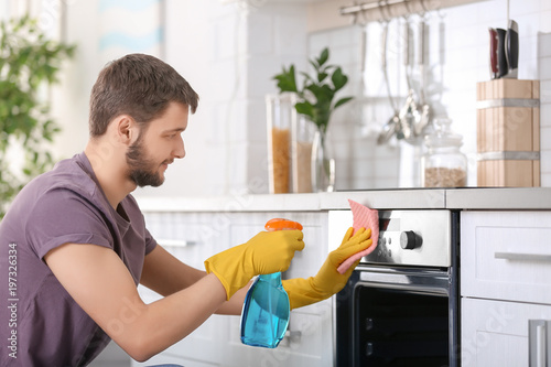 Young man cleaning oven in ...