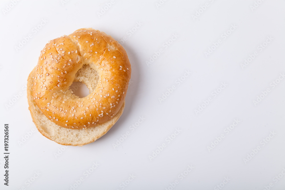Fresh baked bagle bun with sesame seeds on white background pre-cut for making sandwiches Fresh baked bagle bun with sesame seeds on white background pre-cut for making sandwiches