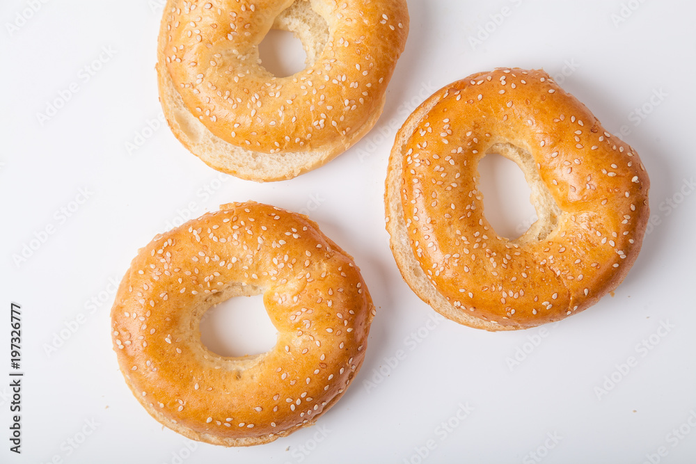 Three fresh baked bagle buns with sesame seeds on white background pre-cut for making sandwiches Three fresh baked bagle buns with sesame seeds on white background pre-cut for making sandwiches