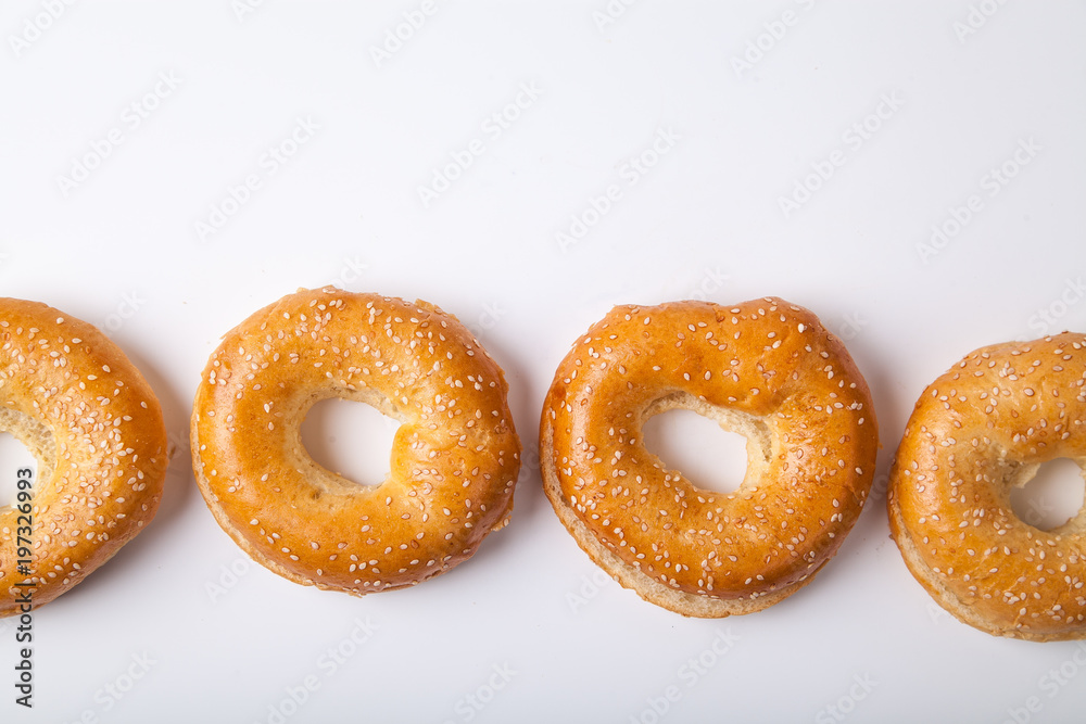 Four fresh baked bagle buns with sesame seeds on white background pre-cut for making sandwiches Four fresh baked bagle buns with sesame seeds on white background pre-cut for making sandwiches