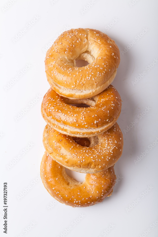 Four fresh baked bagle buns with sesame seeds on white background pre-cut for making sandwiches Four fresh baked bagle buns with sesame seeds on white background pre-cut for making sandwiches