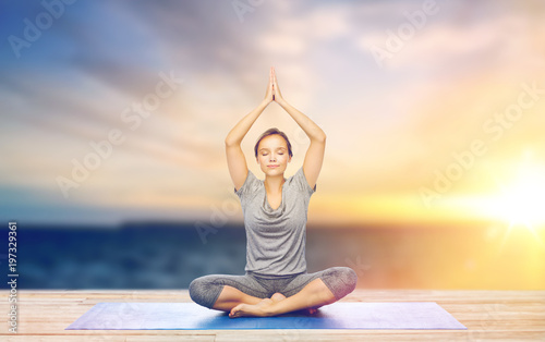 woman meditating in lotus pose on mat outdoors