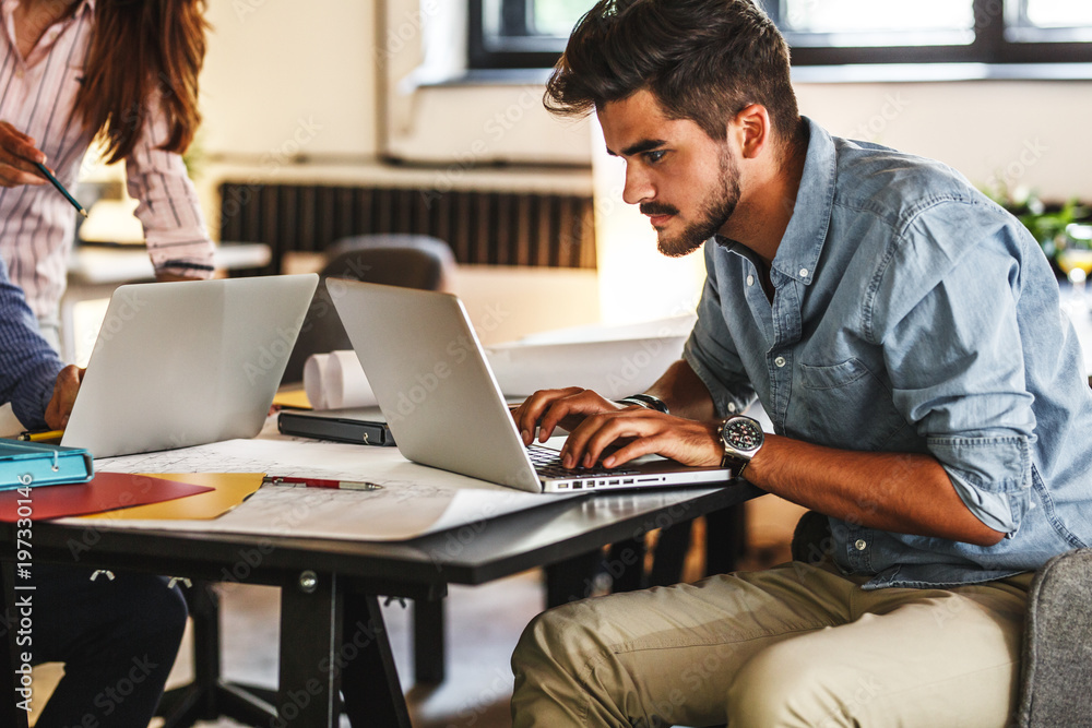 Casual startup programmer and designer working on new project .He sitting at the company cafe and using using laptop. Casual startup programmer and designer working on new project .He sitting at the company cafe and using using laptop.