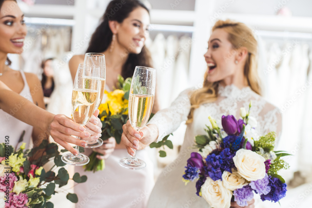 Happy women in wedding dresses toasting with champagne in wedding fashion shop Happy women in wedding dresses toasting with champagne in wedding fashion shop