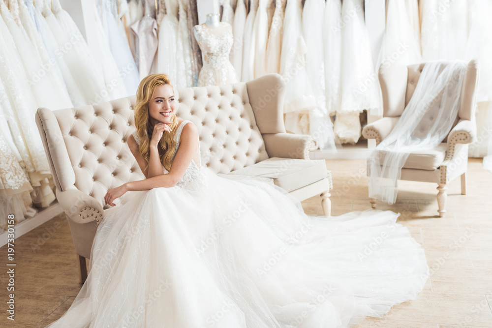 Obraz na plátně Young bride in tulle dress sitting on sofa in wedding salon
