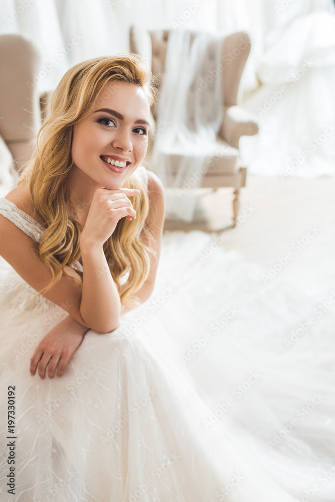 Smiling bride wearing tulle dress in wedding atelier