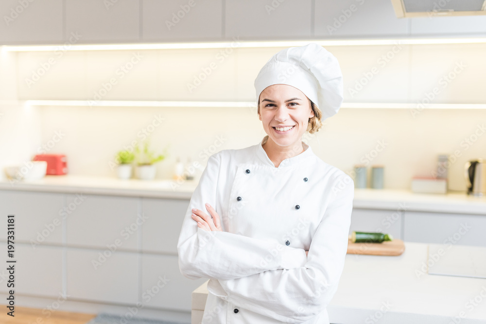 Beautiful young woman chef cooking in modern kitchen