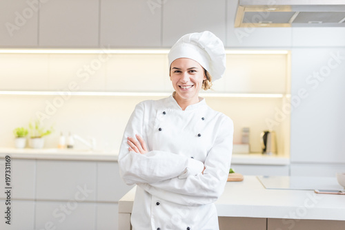 Beautiful young woman chef cooking in modern kitchen