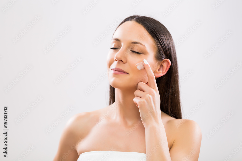 Beautiful  woman applying moisturizer on face.