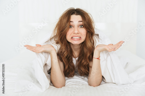 Portrait of a confused young woman lying in bed
