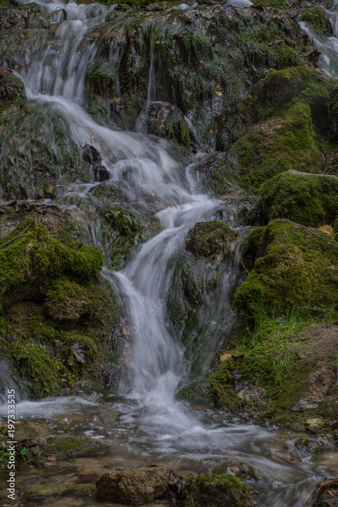 Waterfall in the forest. Green moss and stones.