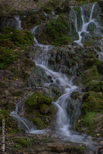 Waterfall in the forest. Green moss and stones.