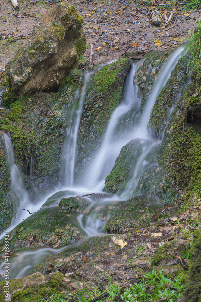 Waterfall in the forest. Green moss and stones.