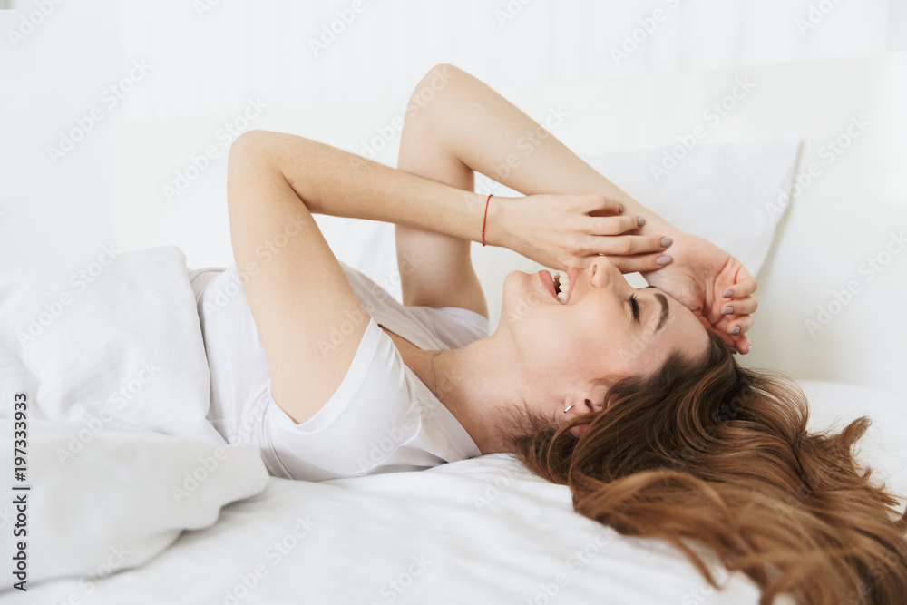 Fototapeta premium Portrait of a laughing young woman laying in bed