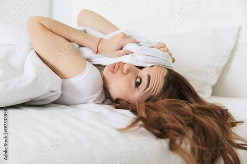 Portrait of a funny young woman laying in bed