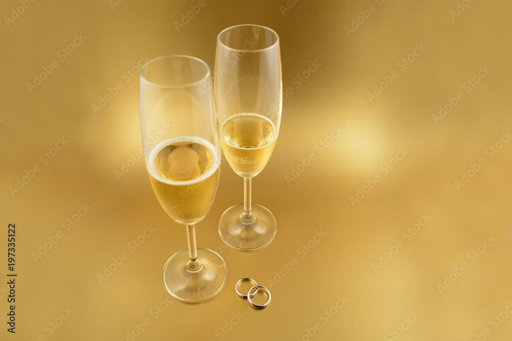 Wedding rings with champagne stock images. Golden wedding background. Valentines Day concept. Champagne on a golden background with copy space for text. Festive golden background