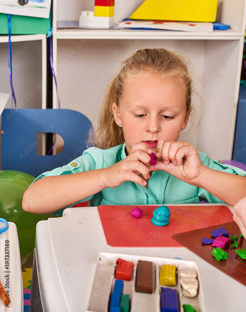 Plasticine modeling clay. Child dough play in school mold from plasticine  in kindergarten. Kids knead modeling clay with hands in preschool.  Preparation for exhibition of crafts made of plasticine. Stock Photo