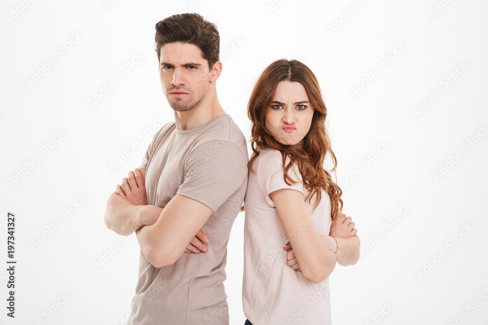 Offended guy and girl wearing beige t-shirts resenting and acting like arguing couple standing back to back with arms crossed, over white background Offended guy and girl wearing beige t-shirts resenting and acting like arguing couple standing back to back with arms crossed, over white background