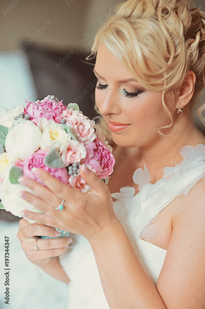 Naklejka premium Beauty bride in bridal gown dress with bouquet and lace veil indoors. Beautiful model girl in a white wedding dress. Female portrait of cute lady. Woman with hairstyle