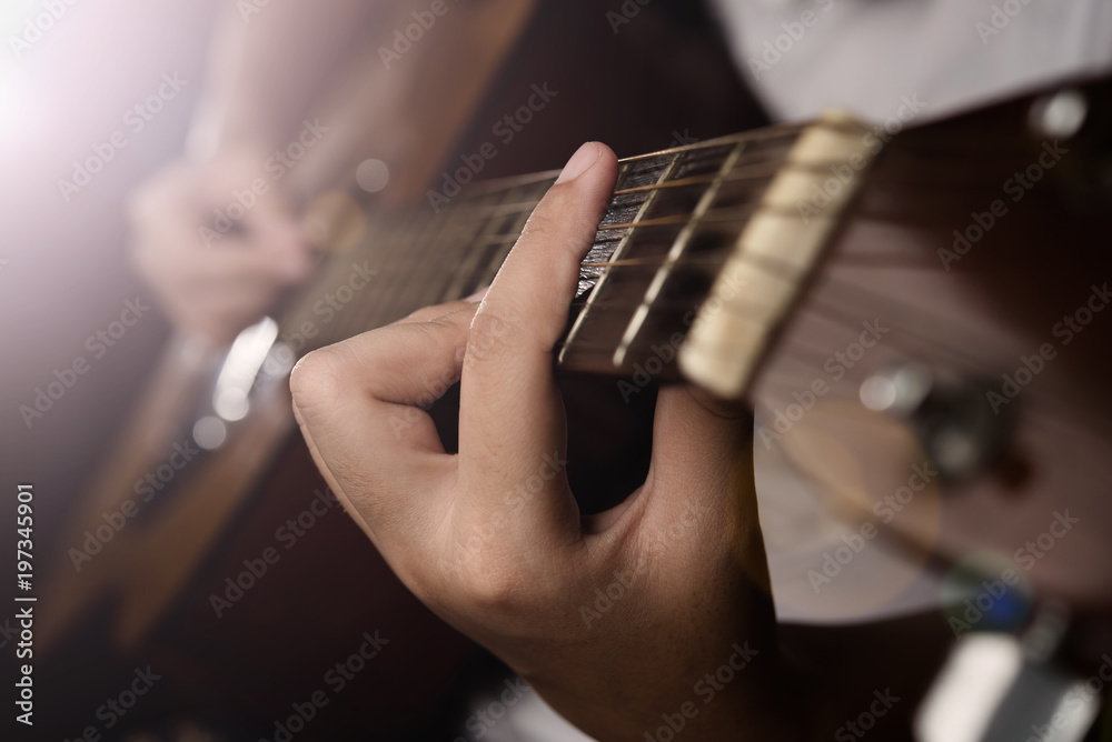 Fototapeta premium Hands playing acoustic guitar with finger catching chord on bar on night bokeh blur background