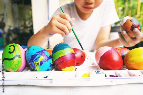 Easter concept, kid painting fancy colorful eggs for Easter event